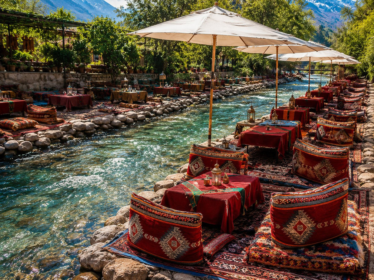 Riverside tables with red cushions and umbrellas along a rushing mountain stream