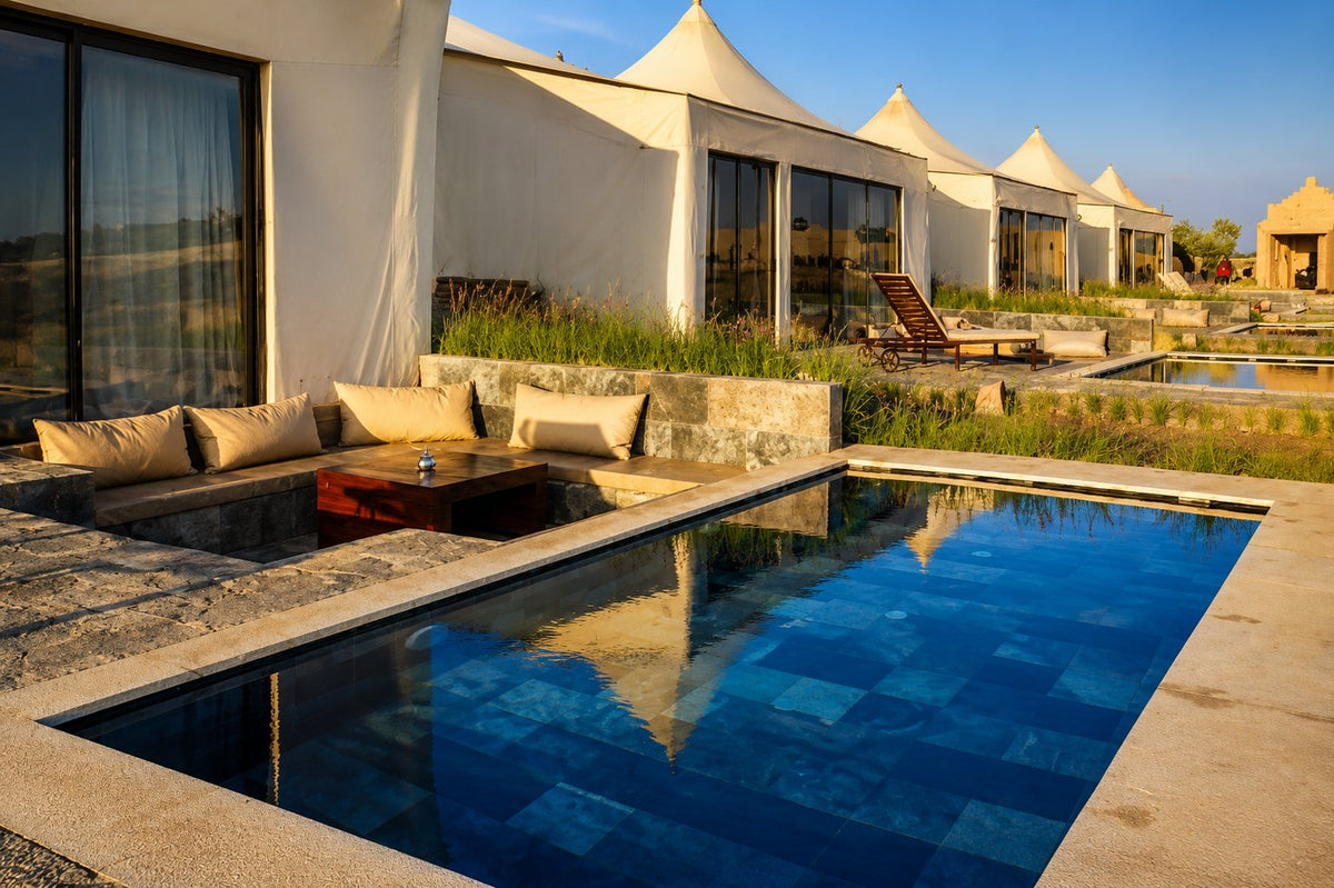 Blue-tiled pool with a sunken lounge beside a row of tented lodges
