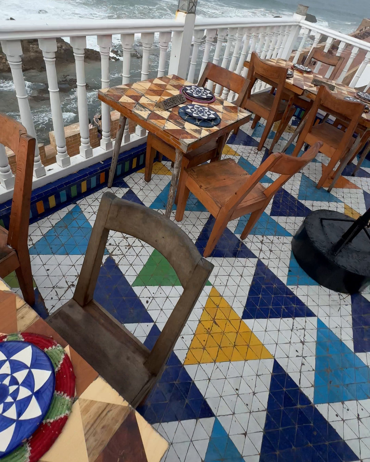 Une terrasse carrelée au-dessus de l'Atlantique à Essaouira, une mouette sur la rambarde.