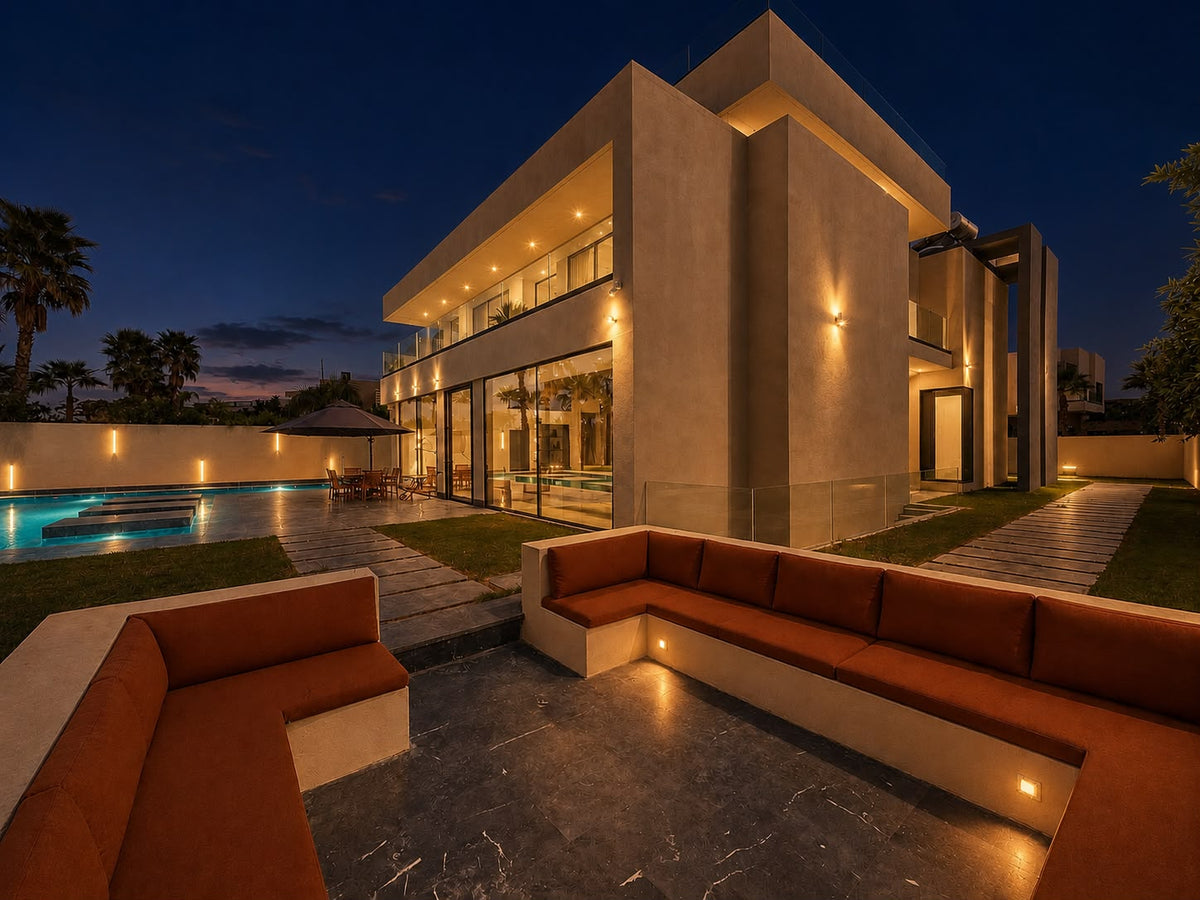 A sunken outdoor lounge lit at night beside the villa