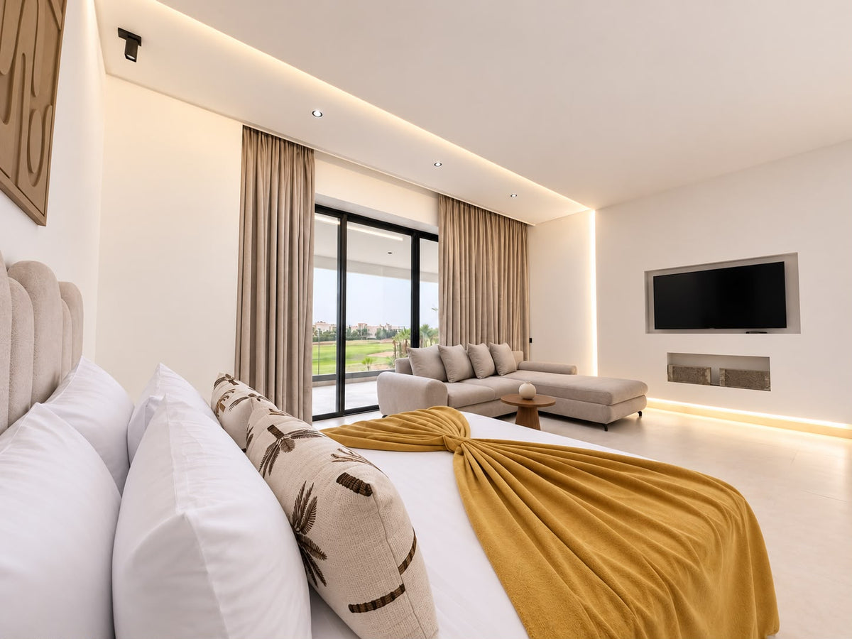 A large bedroom with a mustard throw and a seating corner