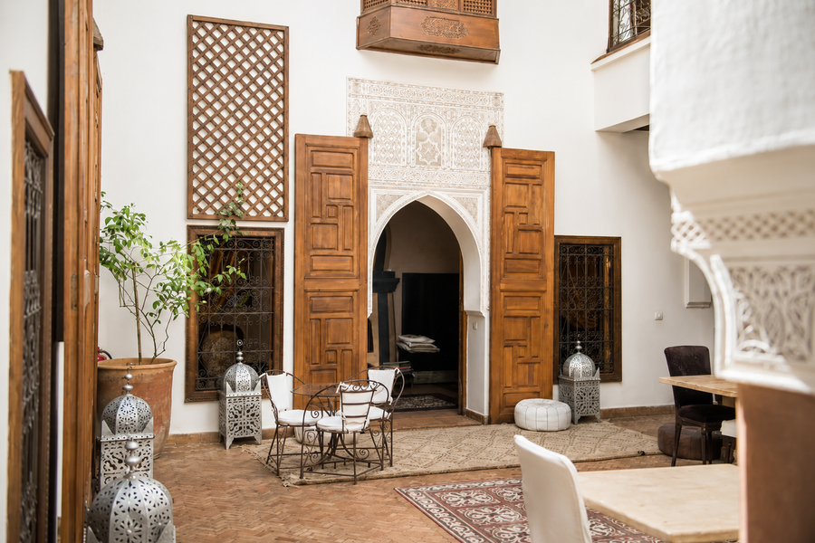 Three generations cooking together around a low table in a Marrakech riad courtyard, Morocco.
