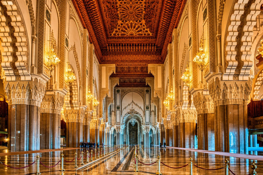 Prayer hall of the Hassan II Mosque with carved columns, chandeliers and a coffered cedar ceiling
