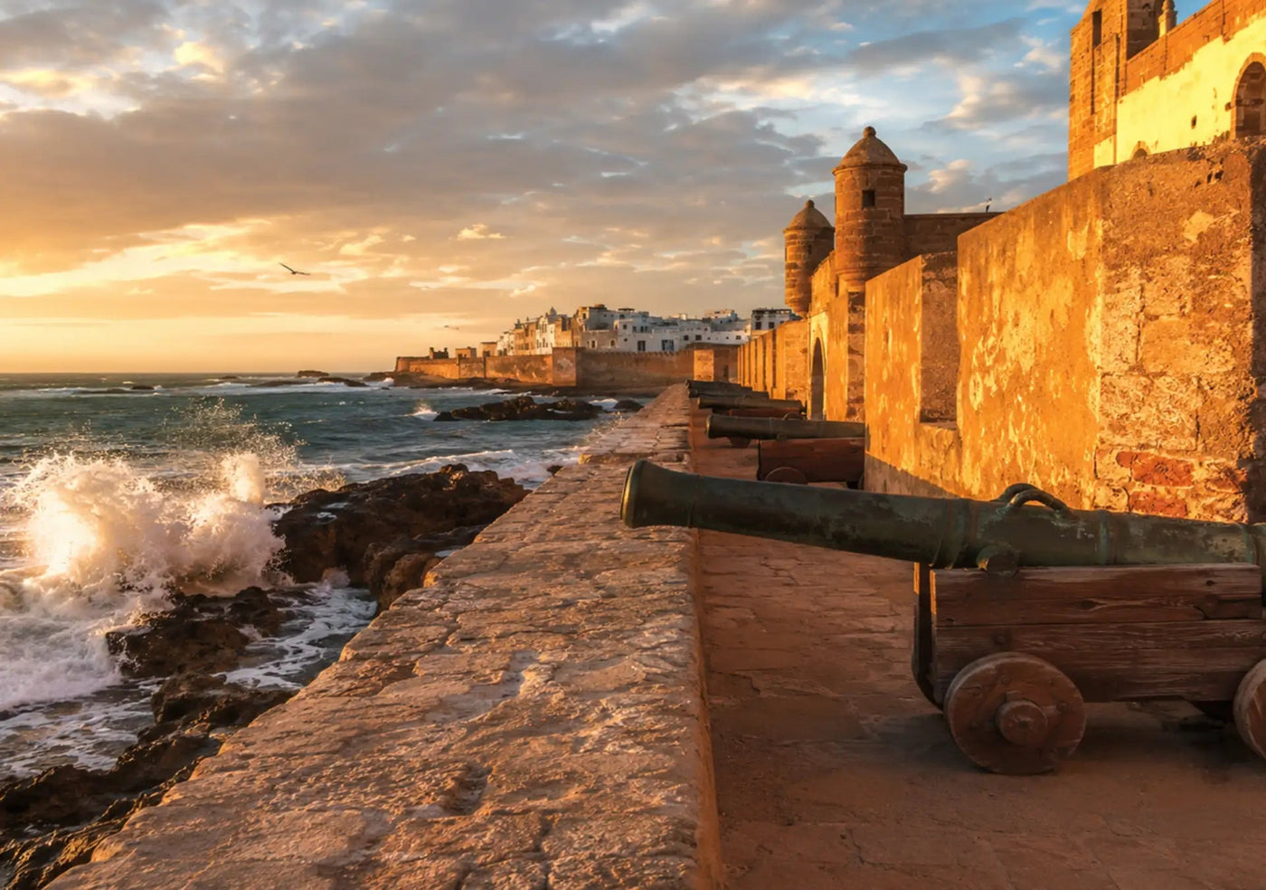 Bronze cannons on the ochre ramparts of Essaouira above waves breaking on the rocks