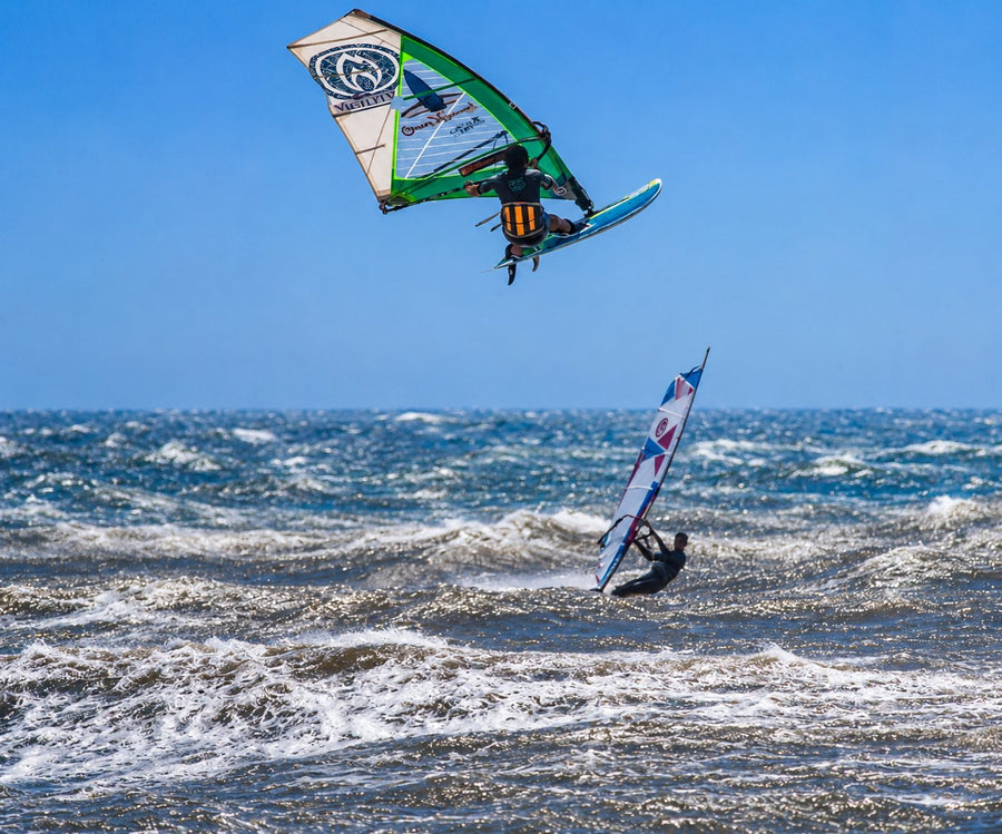 A surf instructor and beginner on the glassy morning bay at Essaouira with the medina ramparts behind, Morocco.
