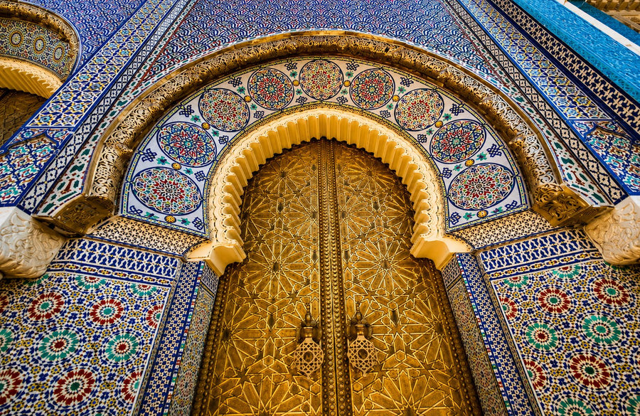 Ornate brass doors framed by blue and green zellige tilework in Fes