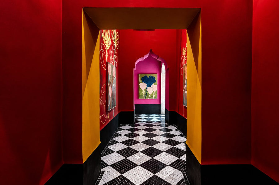 Red and yellow corridor with a black-and-white checkered floor leading to a pink arched doorway