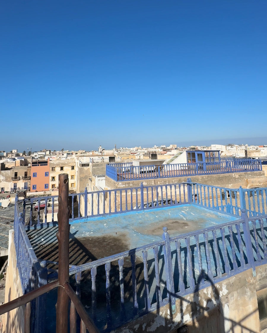 Rooftop terraces of the Essaouira medina running down to the sea under a clear sky.