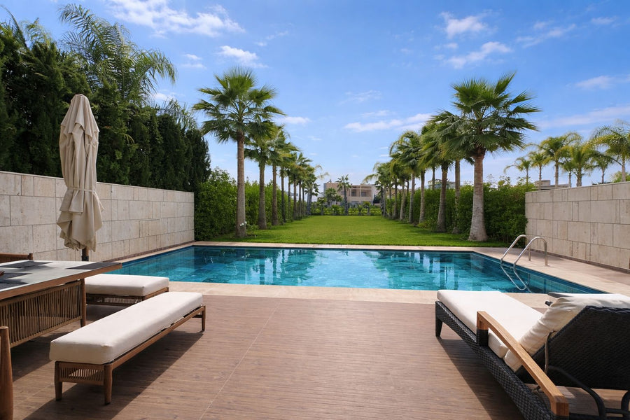 A long pool between two rows of palm trees in a private villa garden in Marrakech