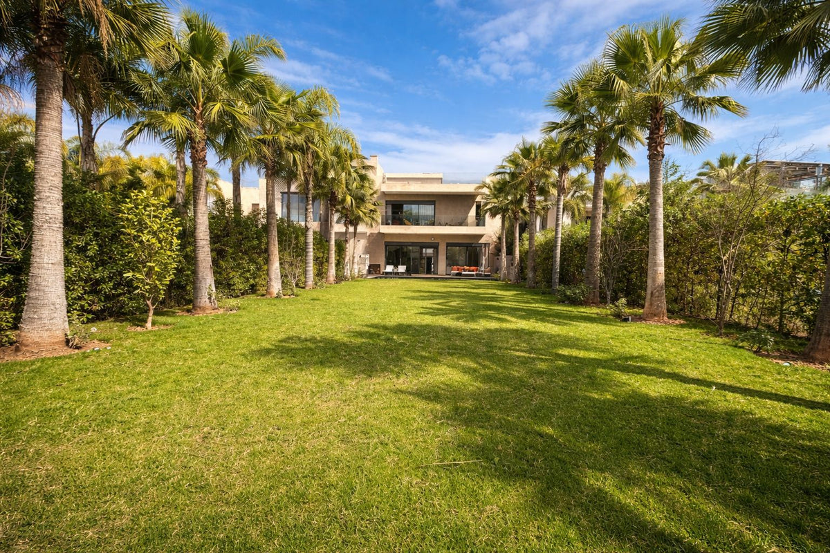 A long lawn lined with palm trees leading to the villa