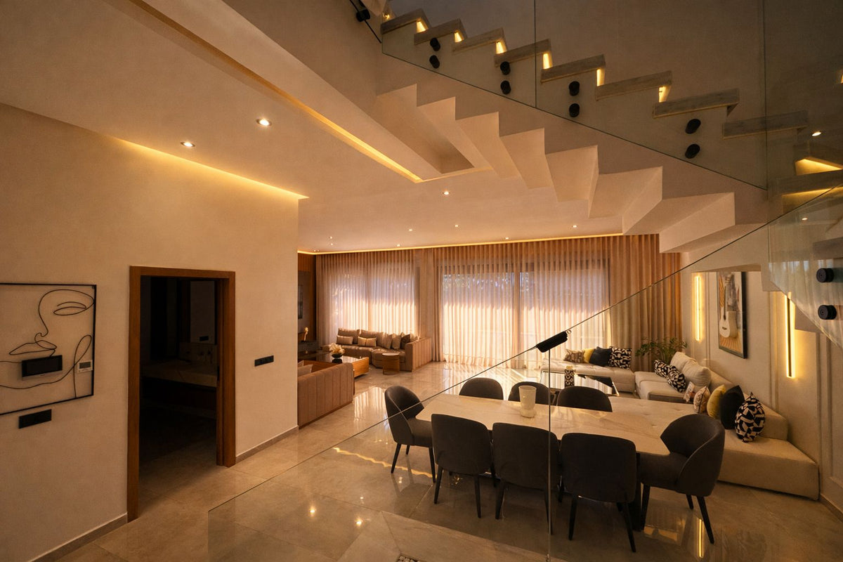 A dining area with a long table near a wooden staircase