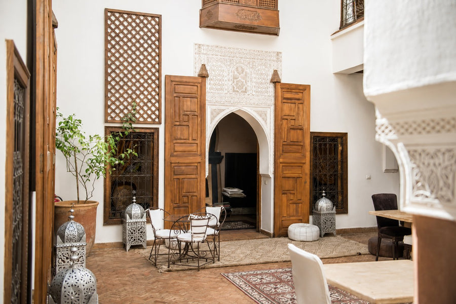 Three generations cooking together around a low table in a Marrakech riad courtyard, Morocco.